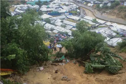  ?? Photograph: Shafiqur Rahman/AP ?? Rescuers carry umbrellas as they search for survivors after heavy rains caused a landslide in Cox’s Bazar, Bangladesh, 27 July 2021.