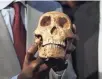  ??  ?? A replica Homo naledi skull is held at an unveiling Tuesday at the Maropeng Museum, near Magaliesbu­rg, South Africa.