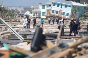  ??  ?? First responders and residents walk along a main street following Hurricane Michael in Mexico Beach, Florida.