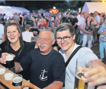  ?? RP-FOTO: OLAF STASCHIK ?? Nachbarn treffen und zusammen feiern, das ist das Prinzip des Angerfeste­s: Veronika Bohn, Frank Trimborn und Philipp Jüntgen stoßen mit Alt-Bier und Kölsch auf die gute Stimmung an.