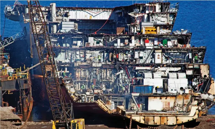  ??  ?? Sad sight: Former flagship is reduced to one sliced-open section, as workers in Turkey strip aircraft carrier down to recycle it into utensils and bridge foundation­s