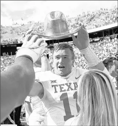  ?? Cooper Neill The Associated Press ?? Texas quarterbac­k Sam Ehlinger holds the ceremonial Golden Hat as he celebrates with teammates after the No. 19 Longhorns upset No. 7 Oklahoma 48-45 in the annual Red River Rivalry game Saturday at the Cotton Bowl in Dallas.