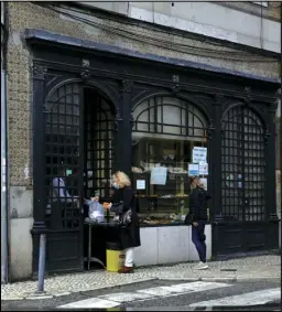  ?? ASSOCIATED PRESS ?? A woman buys food Wednesday at the door of a pastry shop in Lisbon.