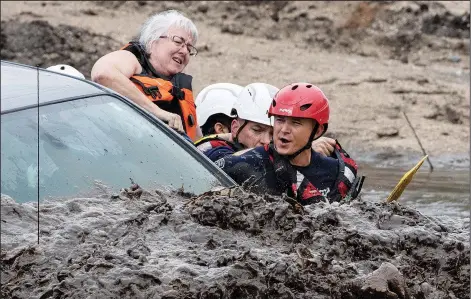  ?? (AP/Arizona Daily Star/Rick Wiley) ?? A woman climbs out of a pickup Aug. 10 as Northwest Fire District firefighte­rs position themselves for a water rescue in the Canada del Oro Wash north of Tucson, Ariz.