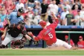  ?? CHRISTOPHE­R PASATIERI/GETTY IMAGES ?? The Phillies’ Michael Saunders slides under the tag attempt of Miami catcher J.T. Realmuto to score.