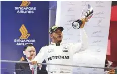  ?? AFP ?? Hamilton celebrates on the podium after winning the Singapore Grand Prix yesterday.