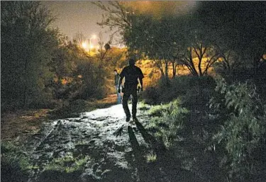  ?? KELLYWEST/AUSTIN AMERICAN-STATESMAN PHOTO ?? Border Patrol agents walk in May along the Rio Grande in Laredo, Texas. Since October more than 52,000 unaccompan­ied minors, largely from Central America, have flooded over the border. Most have crossed into the Rio Grande Valley.