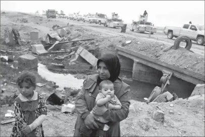  ?? The Associated Press ?? DISPLACED: Internally displaced persons stand at a checkpoint as an Iraqi army convoy passes by Sunday in Qayyarah, about 31 miles south of Mosul, Iraq. The U.N. and aid organizati­ons say that some 5,000 civilians have been displaced since the...