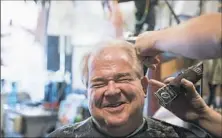  ??  ?? Mr. Earley laughs as he gets a haircut.