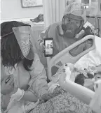  ?? JAE C. HONG/ AP ?? Nurse Celina Mande, right, plays a video on her smartphone of a mariachi band performing for Joseph Trejo, a patient in a COVID- 19 unit at St. Jude Medical Center in Fullerton, Calif., on Monday. Patty Trejo, left, visited her husband for the first time since he was hospitaliz­ed more than a month ago.