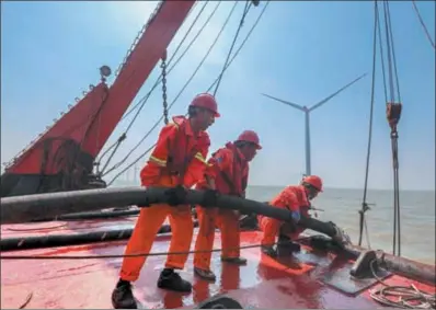  ?? YAO FENG / FOR CHINA DAILY ?? Employees lay an undersea power cable for an offshore wind farm in Zhoushan, Zhejiang province, in September.