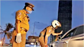  ??  ?? Police officers on curfew duty in Colombo