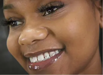  ?? Steve Mellon/Post-Gazette ?? Indya Dawkins, 18, of Penn Hills, shows off tiny Swarovski crystals applied to her teeth. The largest tooth gem was completed at S-Spa of PGH.