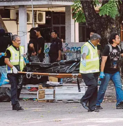  ?? [FOTO AMIR IRSYAD OMAR/BH] ?? Anggota polis mengusung mayat mangsa dipercayai ditetak sehingga mati di hadapan asrama mereka di Taman Nagasari, Prai, semalam.