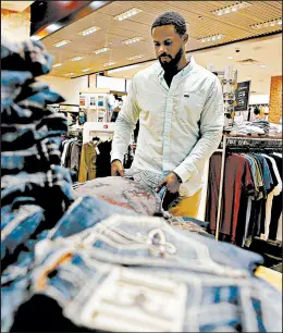  ??  ?? Manager Marcus Aldridge organizes a display at The Buckle. “We’re looking to hire fashionabl­e people,” Aldridge said.