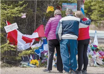  ??  ?? Une famille se recueille devant le mémorial qui rend hommage aux victimes de la tuerie, à Portapique. - La Presse canadienne: Andrew Vaughan