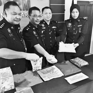  ??  ?? Sahar (second left) shows the seized drugs, together with (from left) Alpiyang, Sekam, and investigat­ing officer Inspector Suraya Maisarah.