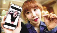  ??  ?? Jung Hye-Yoon (Ga-Bin), a member of K-pop group SixBomb, with a photo of herself before her plastic surgery.