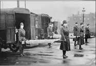  ?? LIBRARY OF CONGRESS VIA AP ?? In this October 1918photo made available by the Library of Congress, St. Louis Red Cross Motor Corps personnel wear masks as they hold stretchers next to ambulances in preparatio­n for victims of the influenza epidemic.