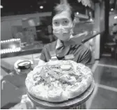  ?? SAKCHAI LALIT/AP ?? A staff member holds a pizza with a cannabis leaf last week at a restaurant in Bangkok, Thailand. The Pizza Company has been promoting its “Crazy Happy Pizza.”