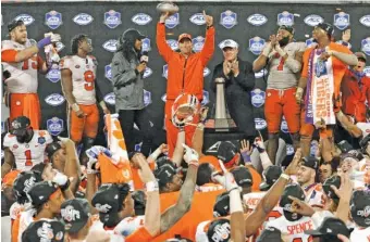  ?? AP PHOTO/MIKE MCCARN ?? Clemson football coach Dabo Swinney raises the trophy after his Tigers won the Atlantic Coast Conference championsh­ip game against Pittsburgh on Saturday in Charlotte, N.C.