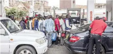  ?? Photograph­er: Patrick Meinhardt/Bloomberg ?? Drivers queue to fill cans with fuel at a gas station in Nairobi, Kenya, on April 13. To try curb inflation and ease pressure on currencies, Kenya and Tanzania have imposed measures, including subsidies on items such as fuel.