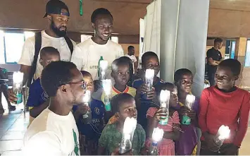  ??  ?? Kids from Makoko holding the solar-powered torchlight­s.