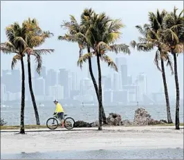  ?? LYNNE SLADKY/AP ?? Arthur is likely to stay well offshore Florida. Above, a bicyclist with a cloudy Miami skyline in the background Friday.
