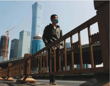  ?? — Reuters ?? A man wearing a protective mask walks by Beijing’s Central Business District during morning rush hour as the spread of the new coronaviru­s disease (COVID-19) continues in China.