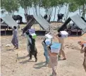  ?? ZAHID HUSSAIN/AP ?? Volunteers arrive to distribute food to flood victims at a camp in Jaffarabad, in Pakistan’s Baluchista­n province, Thursday.