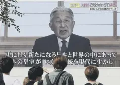  ??  ?? Passers-by watch a screen as Akihito delivers a speech in Tokyo
