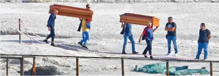  ??  ?? Tragedy: Coffins are carried to the scene as the family’s bodies lie on the ground, covered in sheets