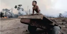  ?? |
Reuters ?? A BOY plays while a fire burns a tract of Amazon jungle as it is cleared by loggers and farmers near Porto Velho, Brazil, this week.