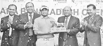  ??  ?? Thitiphun Chuayprako­ng (C) of Thailand receives the championsh­ip trophy after the final round of the Bangladesh Open golf tournament at the Kurmitola Golf Club in Dhaka on February 13, 2016. - AFP photo