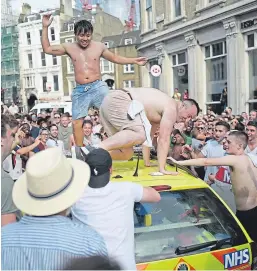  ?? Pictures: Getty. ?? People jump on an ambulance as fans celebrate in the street beside Borough Market in London. Below: A supporter clings to a lamp-post near London Bridge Station.