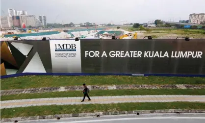  ?? Photograph: Olivia Harris/Reuters ?? A man walks past a 1MDB billboard in Kuala Lumpur in 2015. The now-defunct filed court documents on Friday.