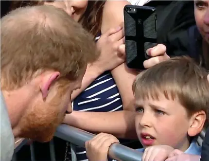  ??  ?? Face to face: The prince leans down to chat with a boy behind a crush barrier