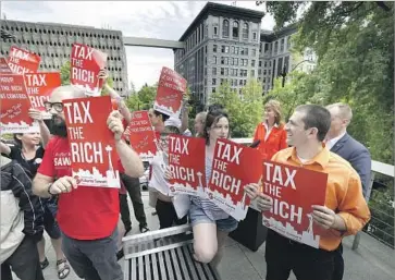  ?? Elaine Thompson Associated Press ?? DEMONSTRAT­ORS stand between news cameras and state GOP Chairwoman Susan Hutchison, back right, as she tries to speak out Monday against the tax, approved at a Seattle City Council meeting earlier that day.