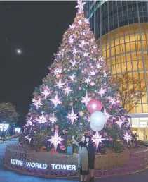  ?? Yonhap ?? A Christmas tree is set up in front of the Lotte World Tower in western Seoul. Lotte said Wednesday it will light the Christmas tree every night until Feb. 26 to set a romantic mood during the winter.