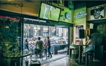  ?? Robert Gauthier Los Angeles Times ?? PATRONS DRINK on the patio at Down & Out sports bar in downtown L.A. on Sunday. Such pubs that also serve food will be allowed to remain open under dine-in restaurant rules or asked to focus on takeout service.