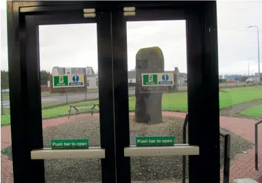  ?? ?? Lochend standing stone viewed through fire doors in an industrial unit