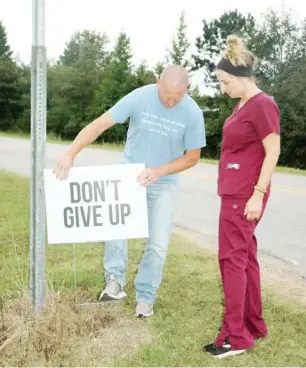  ??  ?? Eric and Leslie Hawes are the force behind the positive words signs that are showing up in the county. Here they are placing one on MS Highway 403. (Submitted Photo)