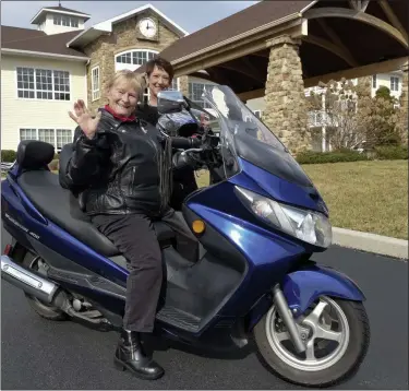  ?? BILL UHRICH — MEDIANEWS GROUP ?? Sigrid “Sigi” Schmidt, 82, is ready to roar off on her Suzuki Burgman 400 touring scooter as Cheryl Anderson, Well By Design Director at the Heritage at Green Hills, readies Sigi’s helmet.