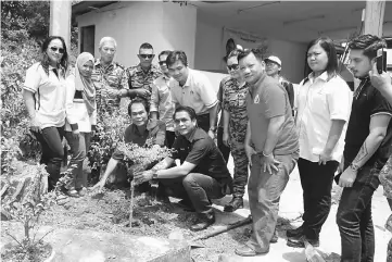  ??  ?? (Squatting, from left) Anyi and Dennis plant a ‘Kayu Anyi’ tree at the end of the work party in Long Bemang.