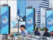  ?? PROVIDED TO CHINA DAILY ?? People walk past signs for the China Internatio­nal Import Expo in Shanghai’s Lujiazui area.