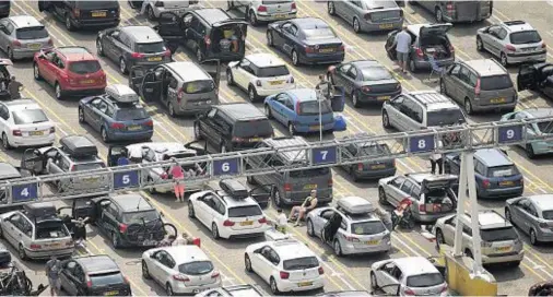  ??  ?? NO PICNIC: Holidaymak­ers sit on deck chairs next to their vehicles at the Port of Dover in Kent after getting stuck for several hours