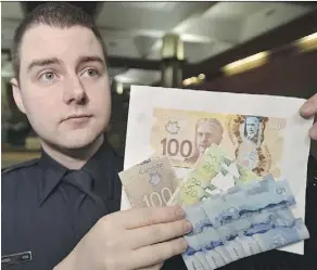  ?? ED KAISER/FILE ?? Const. Zachary Jansen holds up counterfei­t and altered currency police seized during their 2016 investigat­ion of James White.