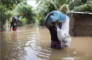  ?? DIEU NALIO CHERY, THE ASSOCIATED PRESS ?? Assilia Joseph, right, and her son Wisner Jean Baptiste, carry belongings they salvaged from their flooded home after the passing of hurricane Irma, in Fort-Liberte, Haiti.