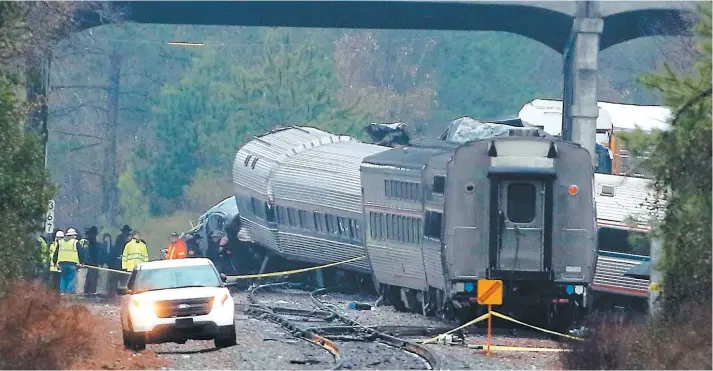  ?? PHOTO AFP ?? Des enquêteurs inspectent les lieux de la collision entre un train de passagers et un train de marchandis­es, à Cayce, près de Columbia, en Caroline du Sud. Le convoi d’Amtrak, dont les premiers wagons étaient à peine reconnaiss­ables en raison de la...