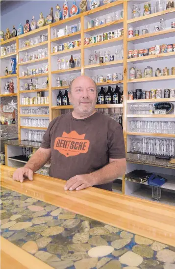  ?? GREG SORBER/JOURNAL ?? Owner Mike Campbell at the bar with inlaid stone on the counter and part of the collection of beer cans and bottles behind him at Drafty Kilt Brewing Co.